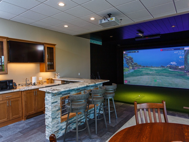 Finished walkout basement is a entertainment center with golf simulator, bar, large screen TV and fireplace.