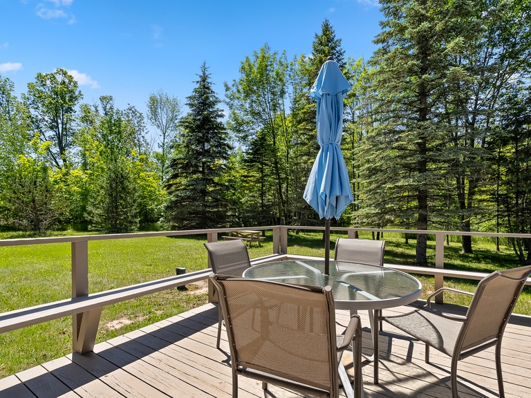 Large outdoor deck includes a table and chairs, and a propane grill