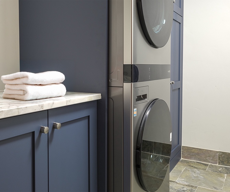 Laundry, Main Level - Stacked washer and dryer with storage cabinetry