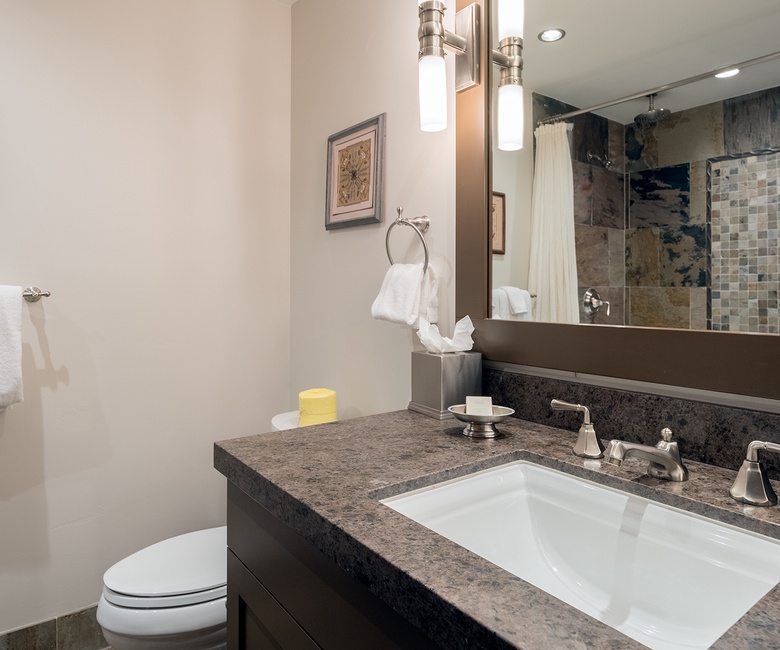 Your beautifully appointed bathroom features elegant granite countertops, a spacious walk-in shower with mosaic tile, and plush white towels ready for your arrival.