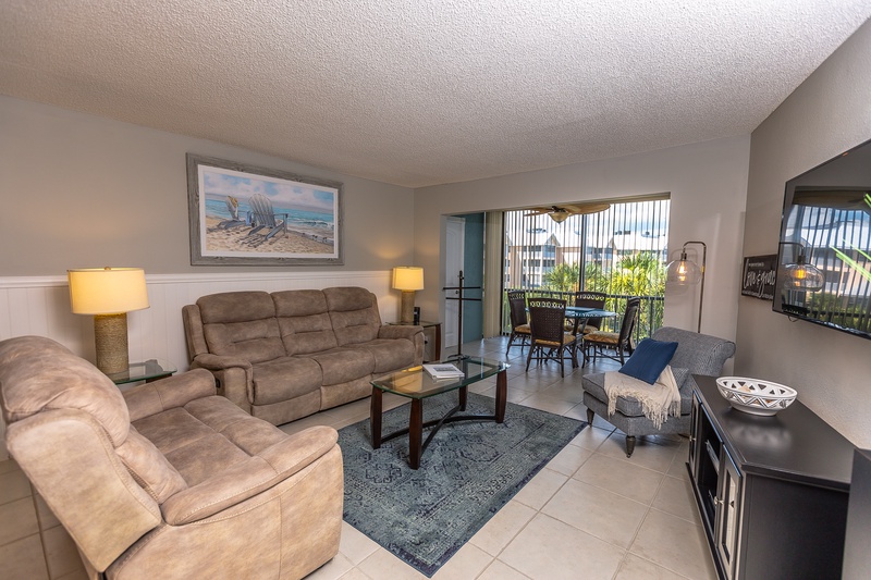 Relax in your spacious living room with plush seating, perfect for unwinding after beach days while enjoying tropical views from your private balcony.