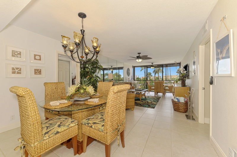 Relax in your tropical dining space with woven furniture and stunning palm tree views through floor-to-ceiling windows.