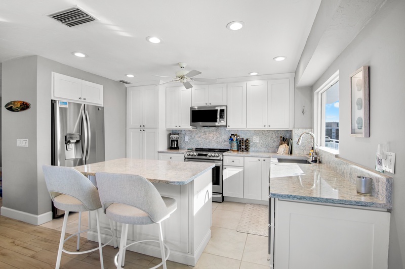 You'll love preparing meals in this bright, modern kitchen with gleaming countertops, stainless steel appliances, and a convenient breakfast bar.