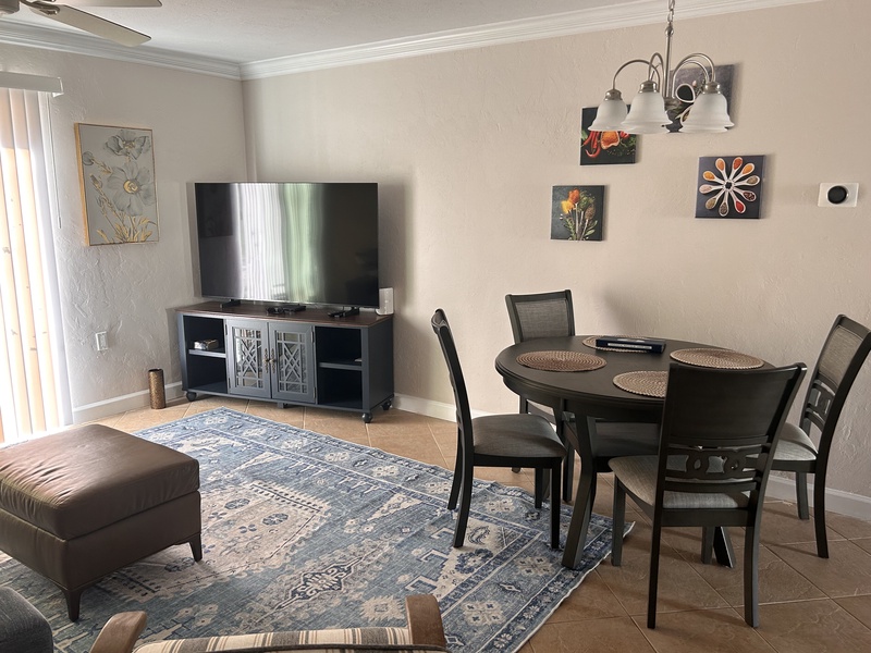 Relax in your open-concept living space featuring comfortable seating, dining for four, and entertainment center—perfect for unwinding after exploring.