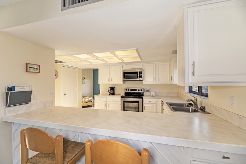 Your fully equipped kitchen awaits with bright white cabinetry, modern appliances, and a breakfast bar where you can start each morning.