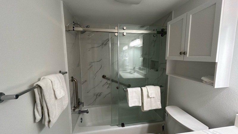 Your sleek modern bathroom features a spacious glass shower with marble-look walls and fresh towels ready for your arrival.