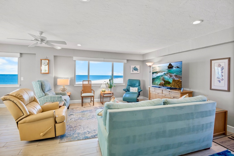 Sink into plush seating while ocean waves fill your view through floor-to-ceiling windows in this bright, coastal-themed living space.