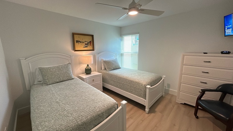 Rest peacefully in your comfortable twin bedroom with ceiling fan, storage, and natural light streaming through the window.