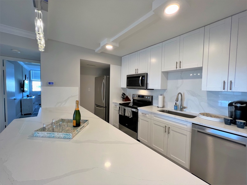 Your sleek kitchen sparkles with white cabinets, marble counters, and stainless steel appliances—perfect for preparing memorable meals.