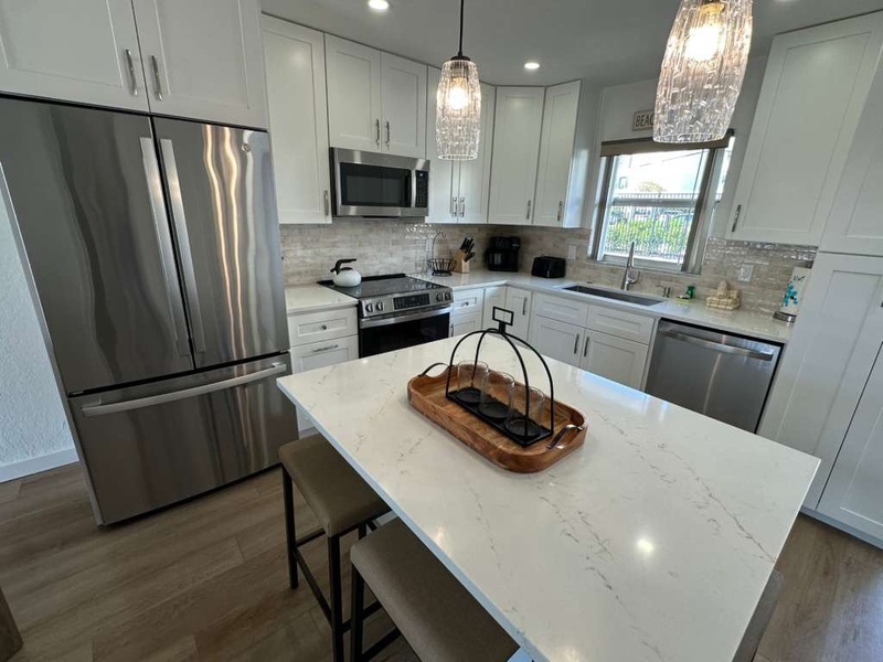 Your gleaming white kitchen features stainless steel appliances, marble countertops, and elegant pendant lighting - perfect for creating memorable meals together.