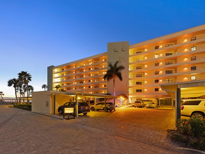 Modern beachfront property with covered parking and elegant evening lighting creates an impressive arrival experience.