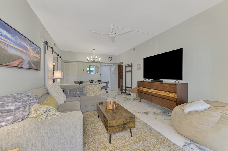 Settle into your spacious living room with plush sectional seating, large smart TV, and stylish mid-century furnishings perfect for relaxing after exploring.