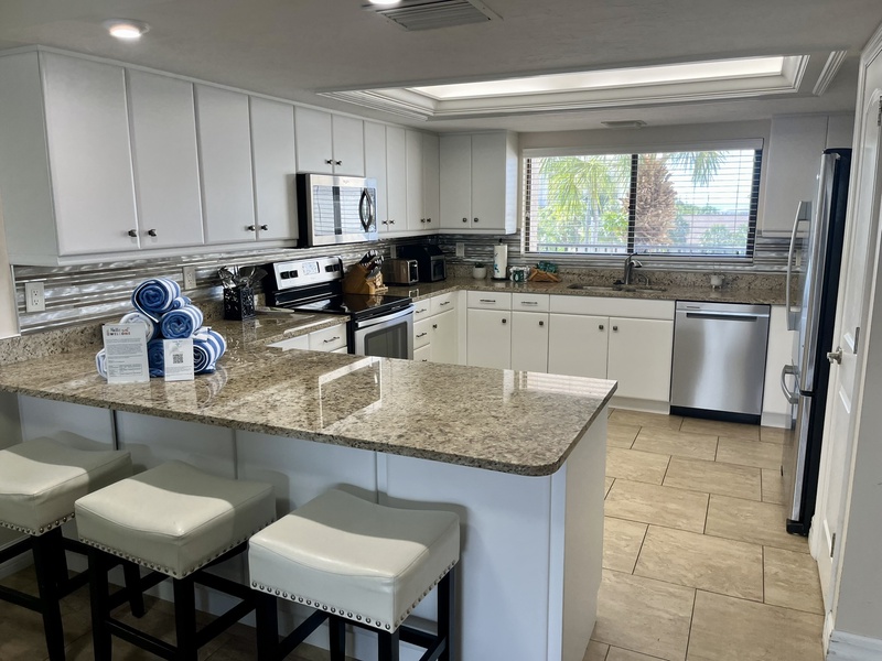 Your spacious kitchen awaits with granite counters, modern appliances, and a sunny breakfast bar perfect for morning coffee.