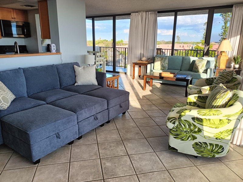 Relax in your tropical-themed living space with comfortable seating, panoramic windows, and stunning views stretching to the horizon.