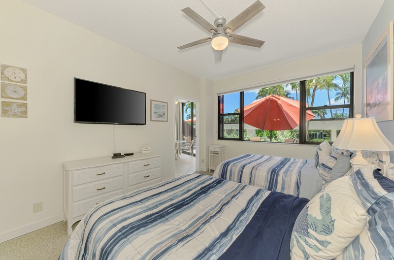 Your bright bedroom features tropical views, ceiling fan, flat-screen TV, and coastal-inspired blue striped bedding for restful nights.
