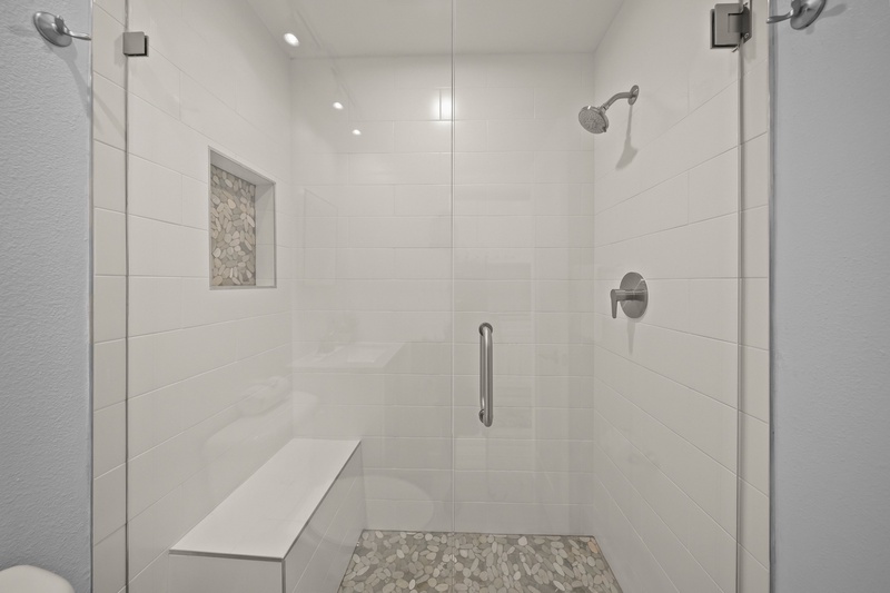 Step into your spacious glass-enclosed shower with modern fixtures, stone accents, and thoughtful built-in seating for ultimate comfort.