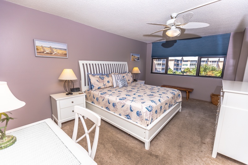 Drift off to sleep in your peaceful bedroom with coastal-themed linens and warm lighting. The ceiling fan keeps you comfortable.