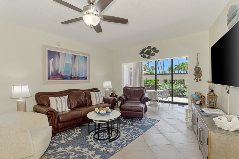 Relax in your inviting living room with plush leather seating, ceiling fan, and tropical views through your private patio doors.