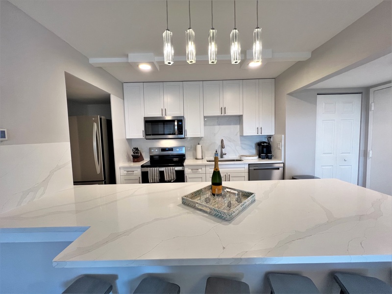 Your modern kitchen awaits with elegant pendant lighting, quartz countertops, and stainless steel appliances perfect for creating memorable meals.