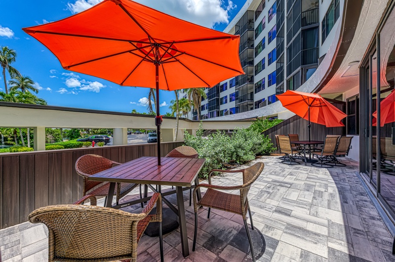 Relax at your private outdoor dining table under bright orange umbrellas, surrounded by modern amenities and tropical landscaping.
