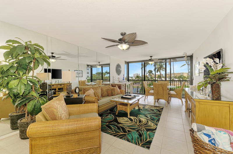 Your bright tropical living space awaits with bamboo furniture, lush plants, and palm views from every window.