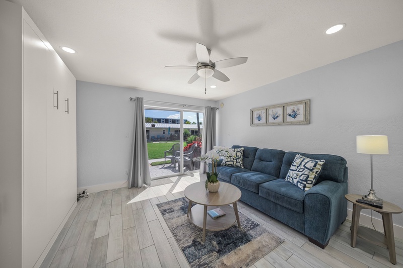 Relax in your bright living space with cozy blue sofa, ceiling fan, and direct patio access to your private yard.