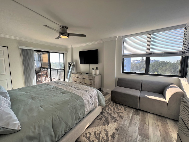 Your spacious bedroom offers comfort with a plush bed, cozy seating area, and private balcony overlooking city views.