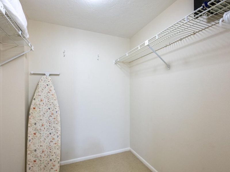 Your spacious walk-in closet features ample storage with wire shelving and a convenient ironing board for all your wardrobe needs.