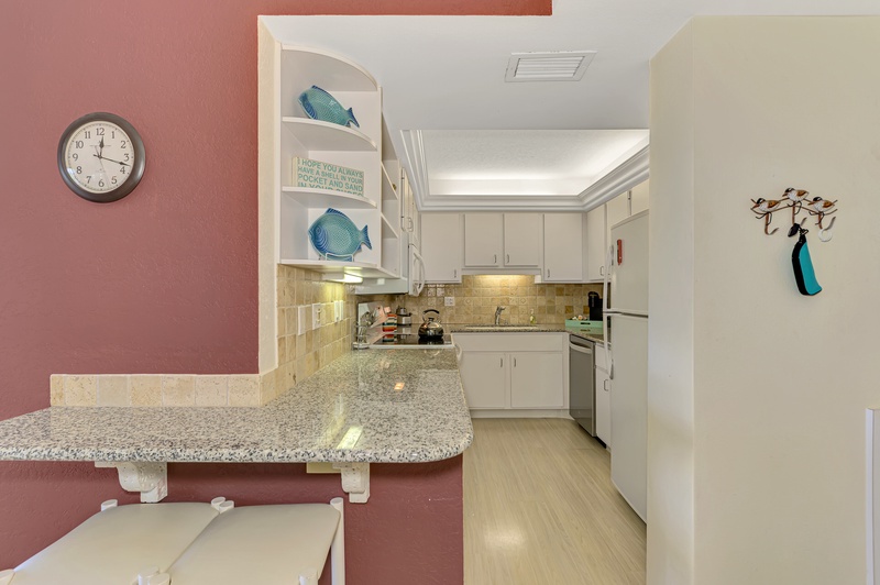 Cook your favorite meals in this bright, fully-equipped kitchen with granite counters, modern appliances, and coastal-themed touches that make you feel right at home.