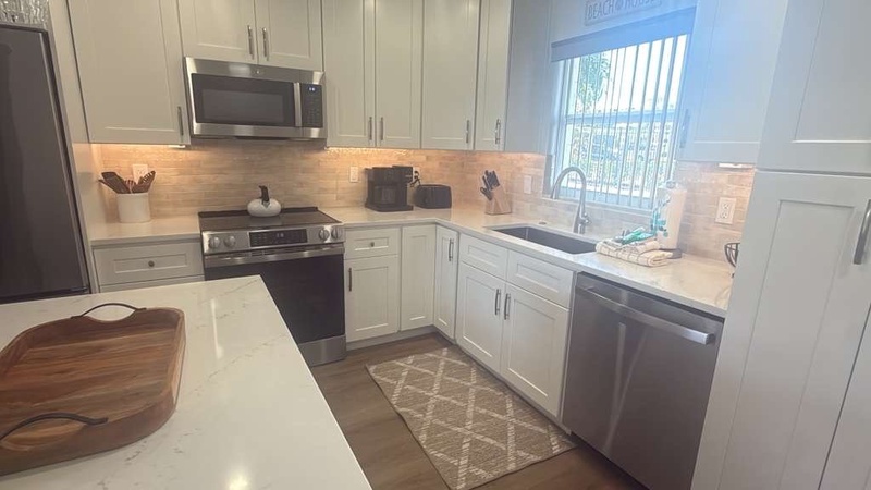 Bright, modern kitchen with pristine white cabinets and granite counters invites you to create memorable meals during your stay.