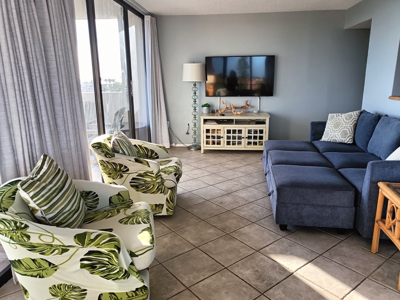 Relax in your bright living room with comfy sectional, tropical accents, and entertainment center - perfect for unwinding after beach days.