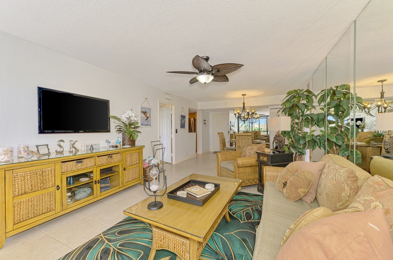 Relax in your tropical-themed living room with comfortable seating, tropical ceiling fan, and entertainment center for cozy evenings.