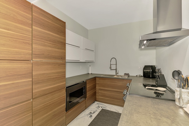 Your sleek modern kitchen features warm wood cabinetry and premium appliances, perfect for creating memorable meals during your stay.