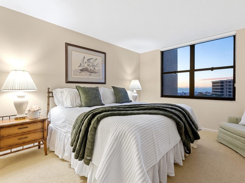 Unwind in your serene bedroom with crisp linens, gentle lighting, and peaceful city views through large windows.