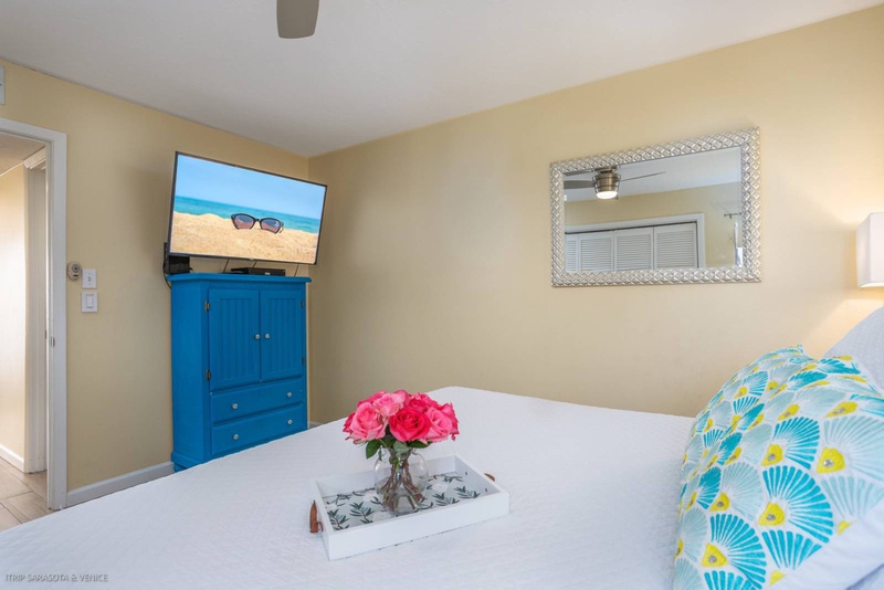 Your bright bedroom features a wall-mounted TV and colorful coastal decor that perfectly complements your beachside getaway.