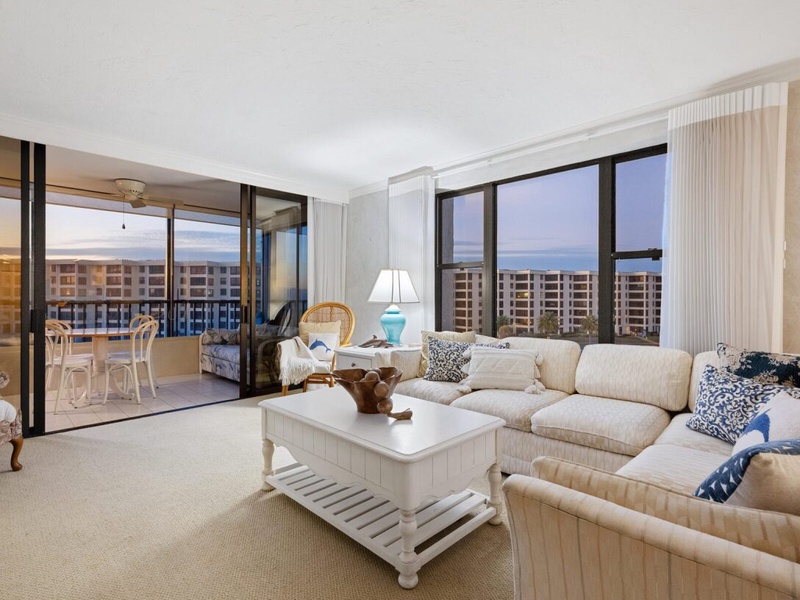 Sink into plush sofas while ocean views stretch endlessly beyond your private balcony in this bright, coastal-inspired living space.