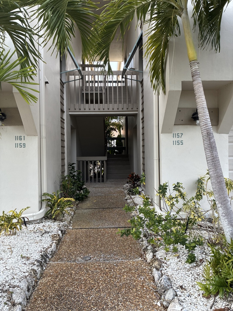 Property entrance with tropical landscaping and distinctive unit numbering system.