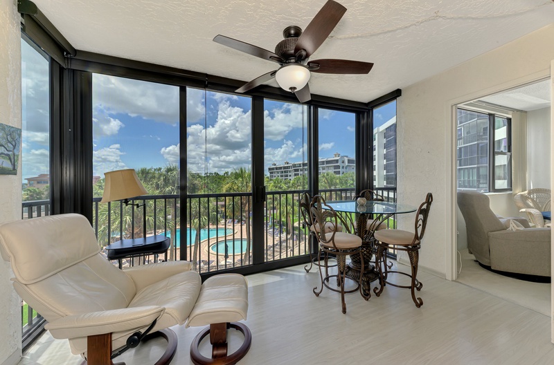 Your bright living space opens to stunning pool views through floor-to-ceiling windows, with cozy seating and dining perfect for morning coffee.