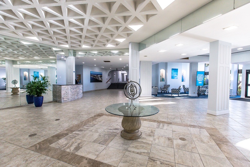 Spacious hotel lobby featuring modern design with geometric ceiling, marble floors, and elegant seating areas for guest comfort.