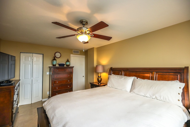 Sink into crisp white linens on your luxurious king bed, where warm wood accents and gentle ceiling fan breezes create your perfect retreat.