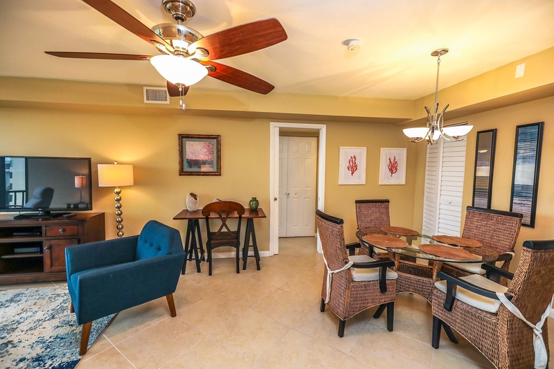You'll love gathering around the elegant glass dining table while the ceiling fan keeps you comfortable in this stylish open-concept space.