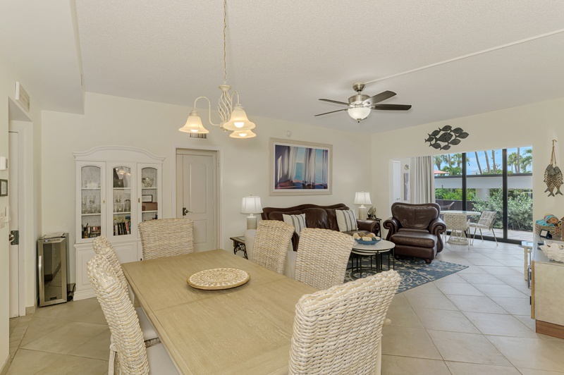 Step into your bright, open-concept living space where coastal charm meets comfort with wicker dining chairs and leather seating.