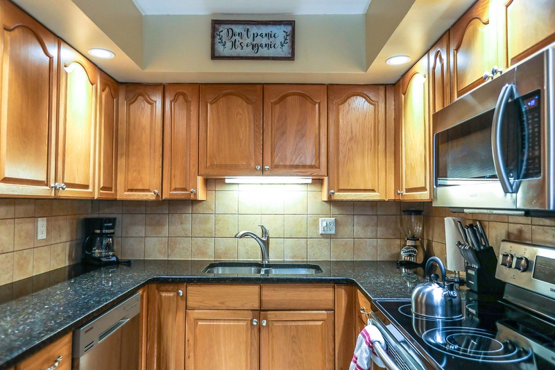Your fully equipped kitchen features warm wood cabinets, granite countertops, and modern appliances for preparing delicious home-cooked meals during your stay.