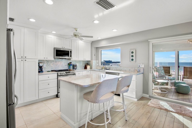 Your modern kitchen features stunning ocean views while you cook and dine at the sleek island with comfortable seating.