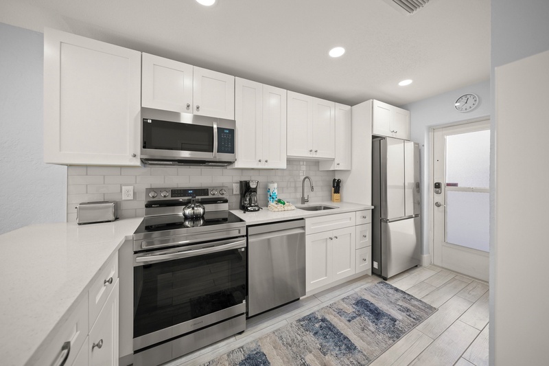 Your fully equipped kitchen features crisp white cabinets, stainless steel appliances, and clean countertops—perfect for preparing home-cooked meals during your stay.