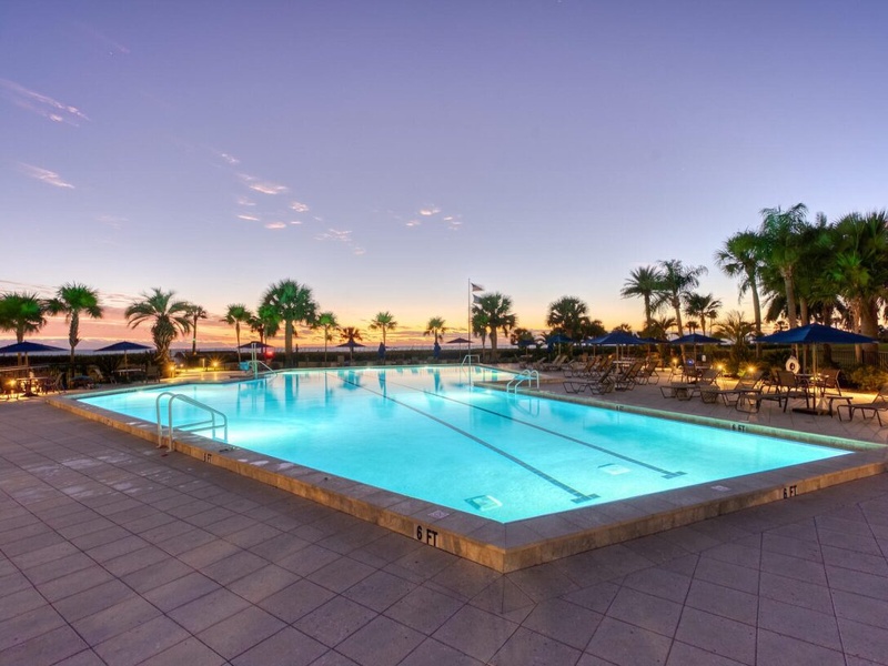 Beautiful poolside setting with tropical palms under a stunning twilight sky, perfect for evening relaxation and scenic views.