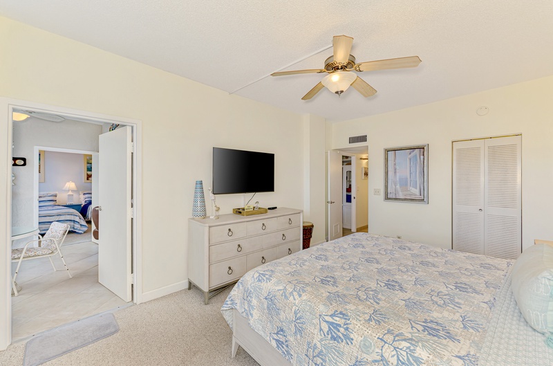 Unwind in your spacious bedroom with coastal-themed bedding, ceiling fan for comfort, flat-screen TV, and plenty of storage space.