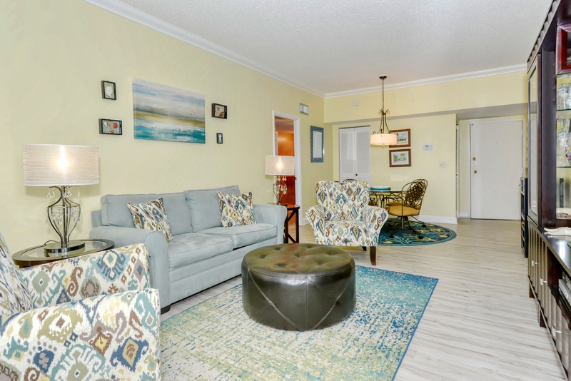 Relax in your bright living space featuring coastal artwork, plush seating, and a seamless flow to the dining area for comfortable gatherings.