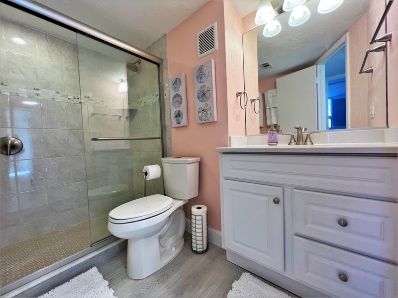 Step into your coastal-themed bathroom featuring a spacious glass shower and elegant vanity with plenty of storage for your belongings.