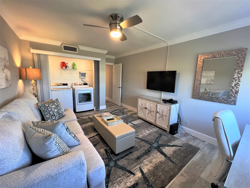 Relax in this stylish living room with plush seating, entertainment center, and convenient in-room laundry facilities for your comfort.